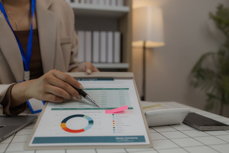 a businesswoman is sitting in her private office working on her desk with many documents to check, a lot of marketing documents were reviewed by the team leaderの写真素材