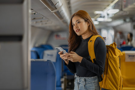 young happy woman in an airplane cabin, a beautiful asian woman travels by plane to a foreign country for vacation, atmosphere inside the plane, a woman performs various poses on an airplane.の写真素材