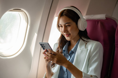 an asian woman is traveling abroad for vacation by plane, female traveler using her electronic...