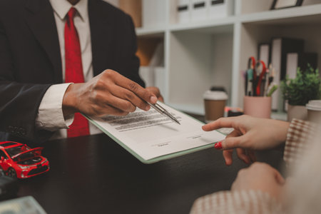 a car salesperson is explaining the details of a car purchase contract to the buyer before signing the sales contract, showroom, dealer, car contract, sining a car purchase contractの写真素材