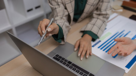 data analysis staff are helping to check data in various documents before summarizing and presenting them to the meeting, two business colleagues working together on paperwork at officeの写真素材