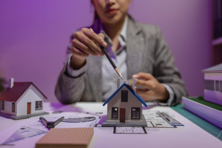 an experienced female engineer is giving a final check to a house model in her private office to make sure it meets the blueprints and meets the construction deadlineの写真素材