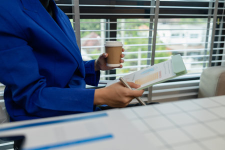 concentrated female entrepreneur working on paperwork while sitting at desk in office, businesswoman is sitting in her office and working, marketing and finance departmentの写真素材