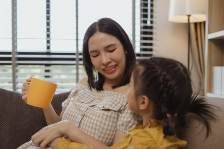 a pregnant mother spent a weekend with her daughter, they did a lot of activities together on the sofa in the living room, family, enjoyment, parent, mother and daughterの写真素材