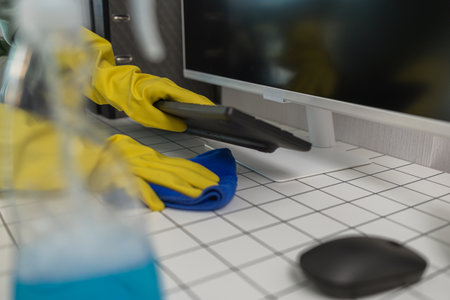 a company's cleaning lady is diligently cleaning the executive's office, the cleaning lady wears rubber gloves to prevent irritation form chemicals while cleaningの写真素材