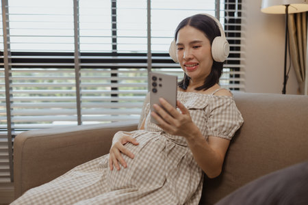 a pregnant mother is relaxing on a sofa in her own home, a woman's pregnancy, family, a woman was very happy because she was pregnant and would soon give birth to her babyの写真素材