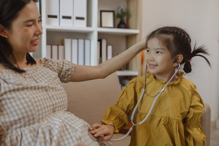a pregnant mother spent a weekend with her daughter, they did a lot of activities together on the sofa in the living room, family, enjoyment, parent, mother and daughterの写真素材