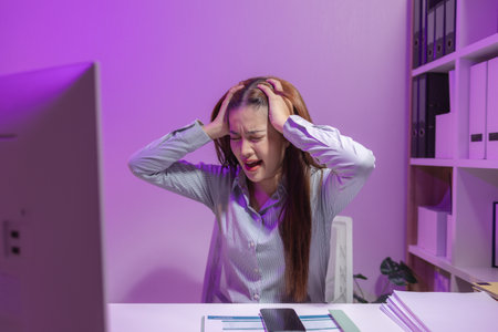a female supervisor is working overtime at the company stressed because there are many documents that need to be solved in time, tired, businesswoman, deadline, overwork, exhaustedの写真素材