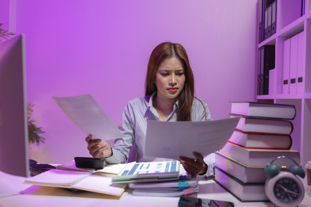 a female supervisor is working overtime at the company stressed because there are many documents that need to be solved in time, tired, businesswoman, deadline, overwork, exhaustedの写真素材