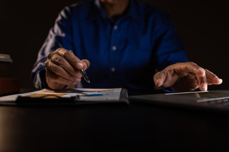 a businessman works overtime is his accounting firm's office until late at night, an entrepreneur remains at his export company because he has a lot of customer documents to checkの写真素材