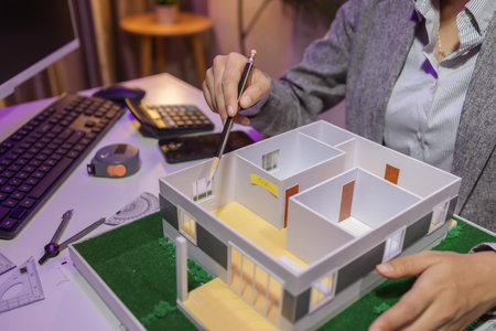 a passionate female architect works in her private office to remodel a house to meet her client's exact needs and meet construction deadlines, house model, engineer, blueprintの写真素材