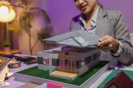 a passionate female architect works in her private office to remodel a house to meet her client's exact needs and meet construction deadlines, house model, engineer, blueprintの写真素材