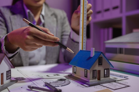 an experienced female engineer is giving a final check to a house model in her private office to...