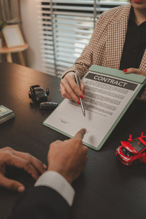 a car salesperson is explaining the details of a car purchase contract to the buyer before signing the sales contract, showroom, dealer, car contract, sining a car purchase contractの写真素材