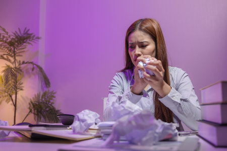 a female supervisor is working overtime at the company stressed because there are many documents that need to be solved in time, tired, businesswoman, deadline, overwork, exhaustedの写真素材