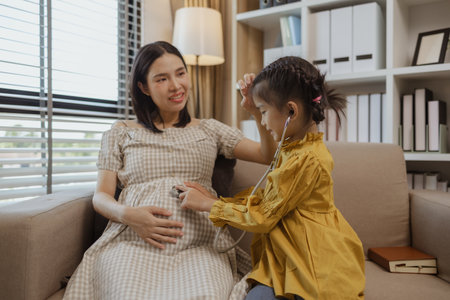 a pregnant mother spent a weekend with her daughter, they did a lot of activities together on the sofa in the living room, family, enjoyment, parent, mother and daughterの写真素材