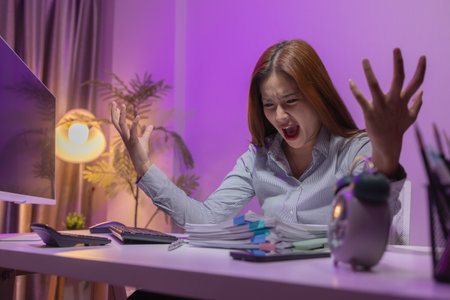a female supervisor is working overtime at the company stressed because there are many documents that need to be solved in time, tired, businesswoman, deadline, overwork, exhaustedの写真素材