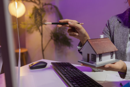 an experienced female engineer is giving a final check to a house model in her private office to make sure it meets the blueprints and meets the construction deadlineの写真素材
