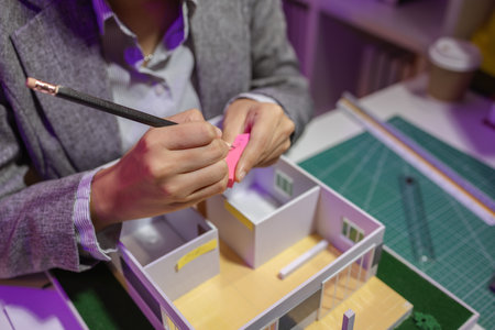 a passionate female architect works in her private office to remodel a house to meet her client's exact needs and meet construction deadlines, house model, engineer, blueprintの写真素材