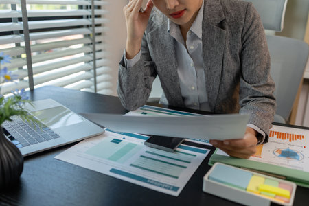 a female employee is feeling very stressed and tired form work, a businesswoman shows signs of extreme fatigue because she has been editing important documents from morning till night, overtimeの写真素材