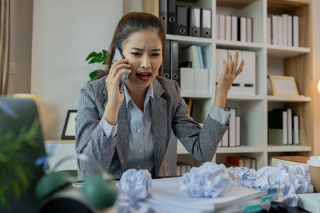 a female employee is extremely stressed at work, a businesswoman is stressed because the deadline for signing a contract is approaching but the documents are not yet completed, serious, upsetの写真素材