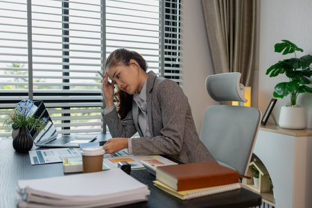 a female employee is feeling very stressed and tired form work, a businesswoman shows signs of extreme fatigue because she has been editing important documents from morning till night, overtimeの写真素材