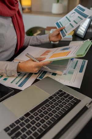 a muslim company employee works in a large financial organization, a muslim female entrepreneur is reviewing her company's financial documents, marketing, accountant, hijab, islamの写真素材