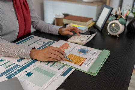 a muslim female employee is working on financial and accounting documents at a company in her private office, hijab, marketing, the female muslim company president is sitting in her office workingの写真素材