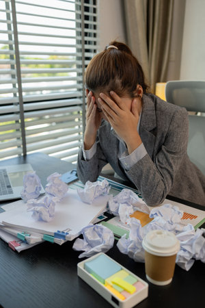 a female employee is extremely stressed at work, a businesswoman is stressed because the deadline for signing a contract is approaching but the documents are not yet completed, serious, upsetの写真素材