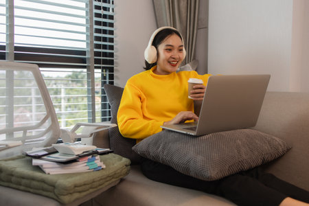 a woman is spending her holiday in the living room of her house, feeling peaceful and happy because she has done many activities that make her feel relaxed, lifestyle, apartment, sofa, couchの写真素材