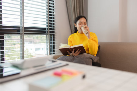 a woman is spending her holiday in the living room of her house, feeling peaceful and happy because she has done many activities that make her feel relaxed, lifestyle, apartment, sofa, couchの写真素材