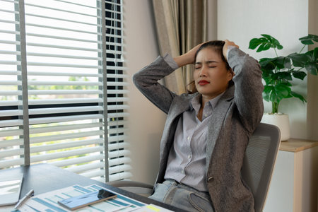 a female employee is extremely stressed at work, a businesswoman is stressed because the deadline for signing a contract is approaching but the documents are not yet completed, serious, upsetの写真素材