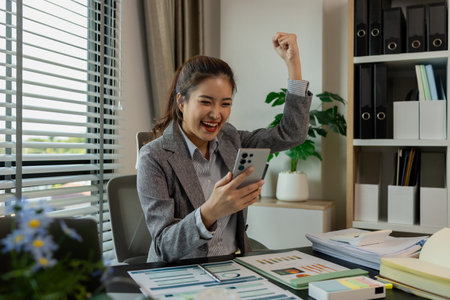 a female employee smiles happily after receiving an email stating that she has been promoted, a businesswoman shows great joy at the face that she has a major investor, finance, marketingの写真素材