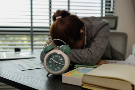 a female employee is feeling very stressed and tired form work, a businesswoman shows signs of extreme fatigue because she has been editing important documents from morning till night, overtimeの写真素材