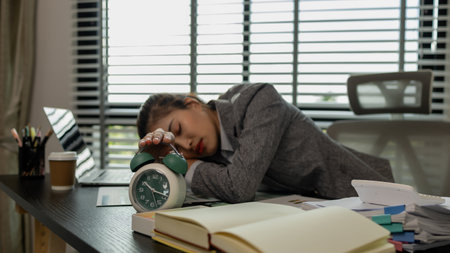a female employee is feeling very stressed and tired form work, a businesswoman shows signs of extreme fatigue because she has been editing important documents from morning till night, overtimeの写真素材