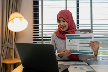 a muslim company employee works in a large financial organization, a muslim female entrepreneur is reviewing her company's financial documents, marketing, accountant, hijab, islamの写真素材