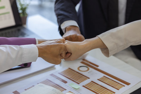 businesspeople are making a high-five gesture or a fist bump or placing their hands together to express their delight at a job well done, employees are sharing their joy at a successful projectの写真素材