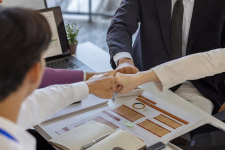 businesspeople are making a high-five gesture or a fist bump or placing their hands together to express their delight at a job well done, employees are sharing their joy at a successful projectの写真素材