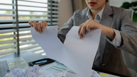 a female employee is extremely stressed at work, a businesswoman is stressed because the deadline for signing a contract is approaching but the documents are not yet completed, serious, upsetの写真素材