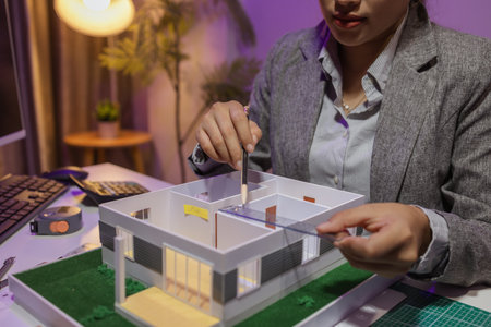 a passionate female architect works in her private office to remodel a house to meet her client's exact needs and meet construction deadlines, house model, engineer, blueprintの写真素材