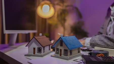 an experienced female engineer is giving a final check to a house model in her private office to make sure it meets the blueprints and meets the construction deadlineの写真素材