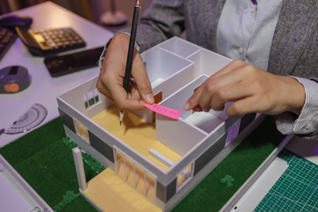 a passionate female architect works in her private office to remodel a house to meet her client's exact needs and meet construction deadlines, house model, engineer, blueprintの写真素材