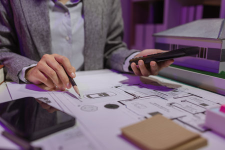 a beautiful female architect is working in her private office because she needs to concentrate on improving the blueprints to be in accordance with the law, engineer, foreman, contractorの写真素材