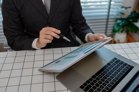 a businessman is sitting at work in his private office, an employee is handling documents to finish on time, accountant, finance, statistics documents, professional, workplaceの写真素材