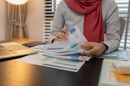 a muslim company employee works in a large financial organization, a muslim female entrepreneur is reviewing her company's financial documents, marketing, accountant, hijab, islamの写真素材