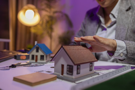 an experienced female engineer is giving a final check to a house model in her private office to make sure it meets the blueprints and meets the construction deadlineの写真素材