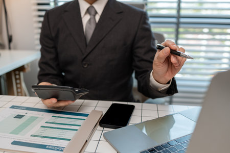 an accountant is calculating financial statements from documents in his private office, finance officer checks company expense documents, businessman works with documentsの写真素材