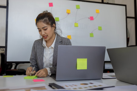 woman is sitting working in a private office, staff is writing a plan to present in a meeting, company work environment,の写真素材