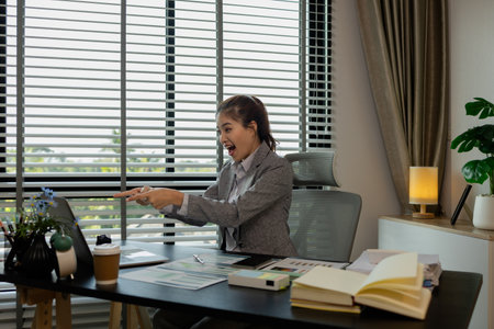 a female employee smiles happily after receiving an email stating that she has been promoted, a...