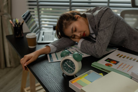 a female employee is feeling very stressed and tired form work, a businesswoman shows signs of extreme fatigue because she has been editing important documents from morning till night, overtimeの写真素材